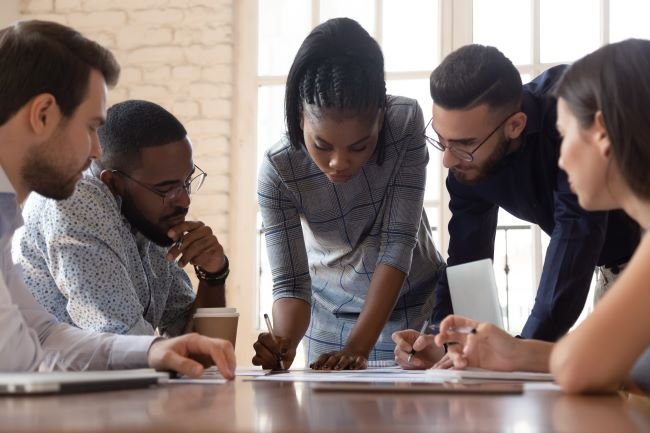 Group of Youth Apprentices gathered around a table and going over business papers