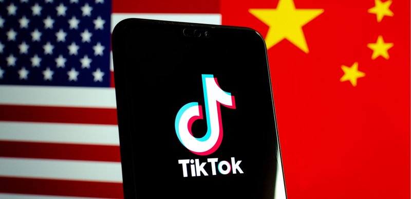 TikTok app logo on a smartphone screen with United States and China flags in background.